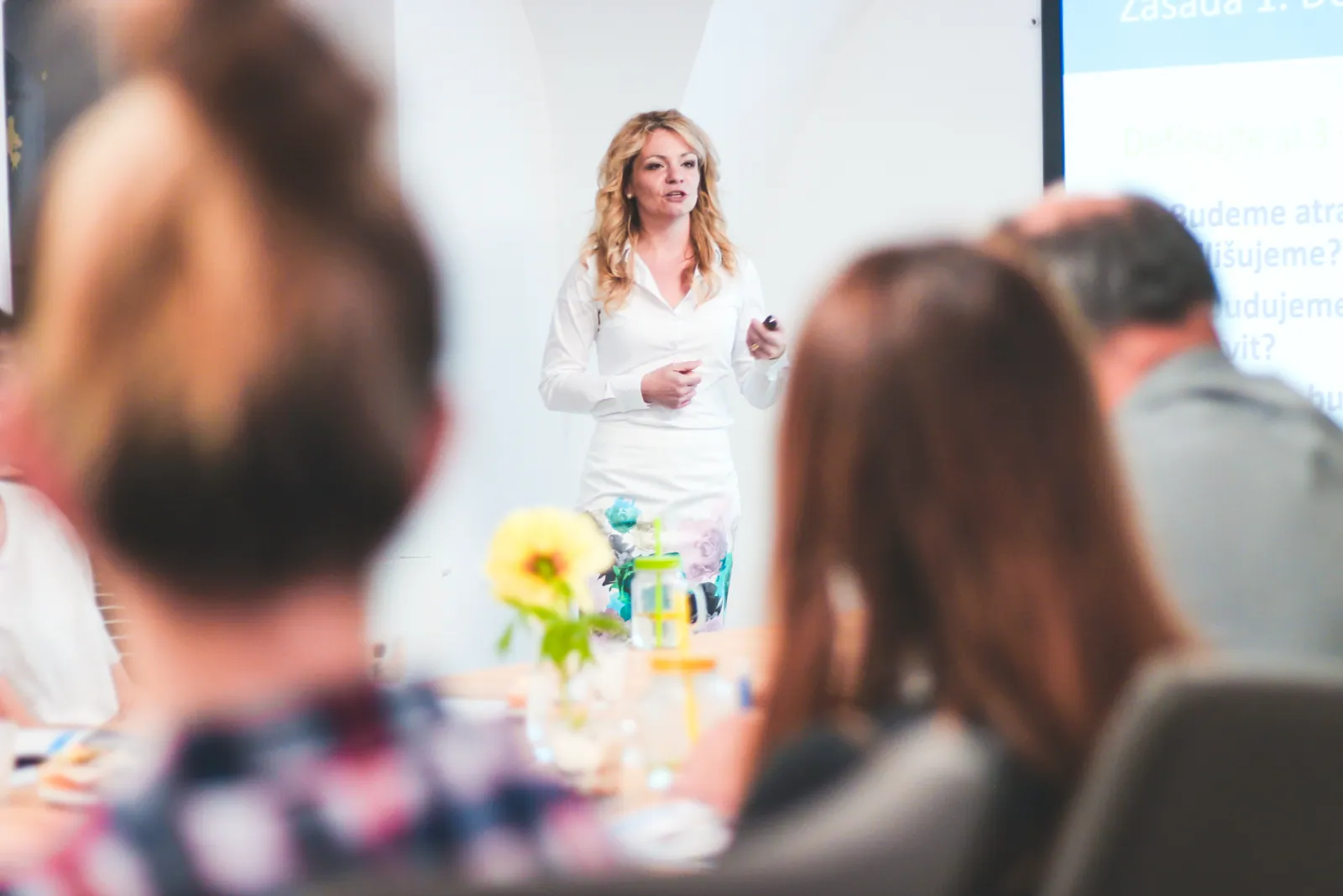 Přednášející v&nbsp;bílé košili vede workshop pro účastníky u&nbsp;stolu